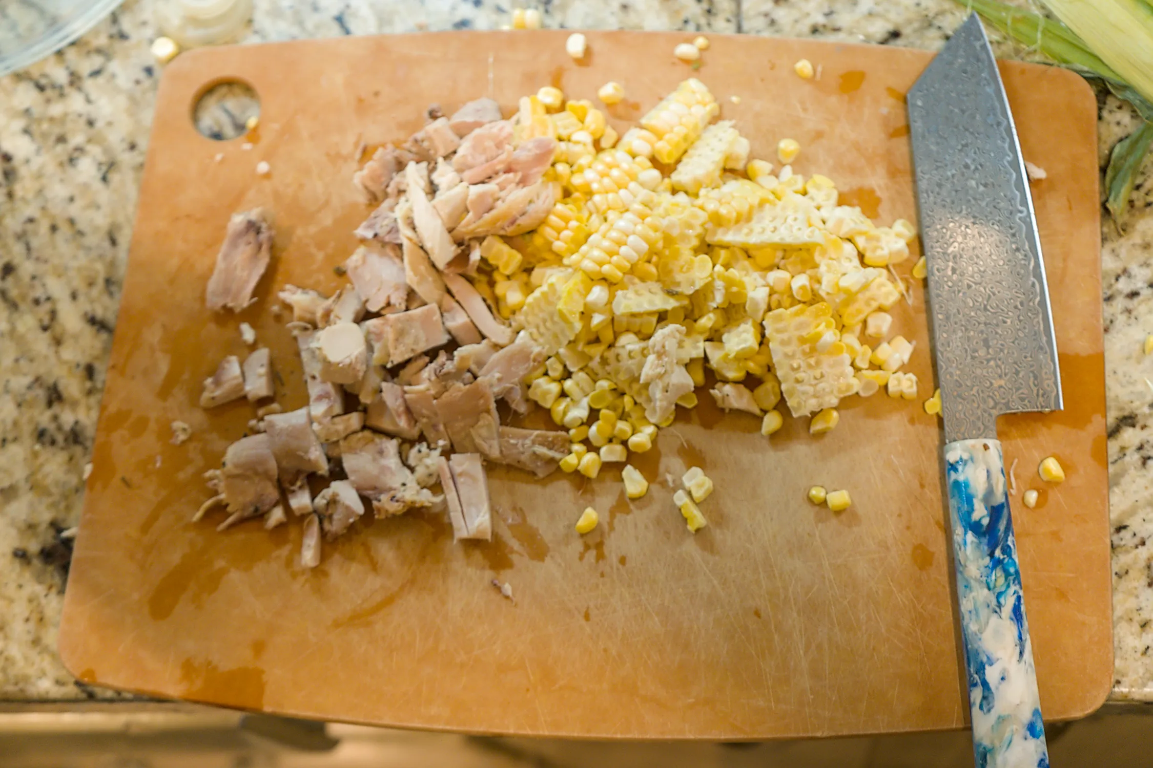 Shredded chicken and corn kernels on a cutting board