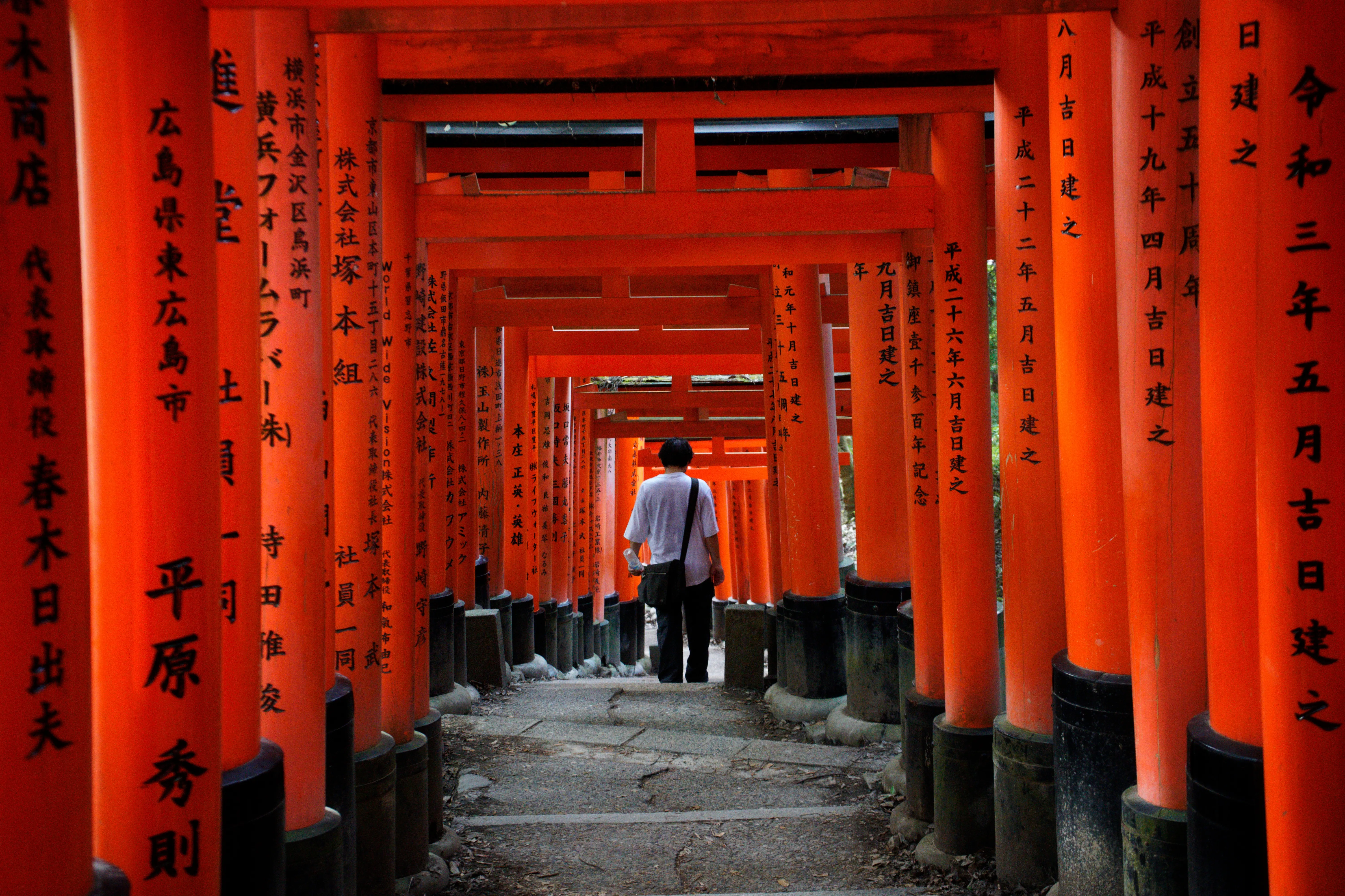 A man walking down the steps under the torii at Fushimi-Inari