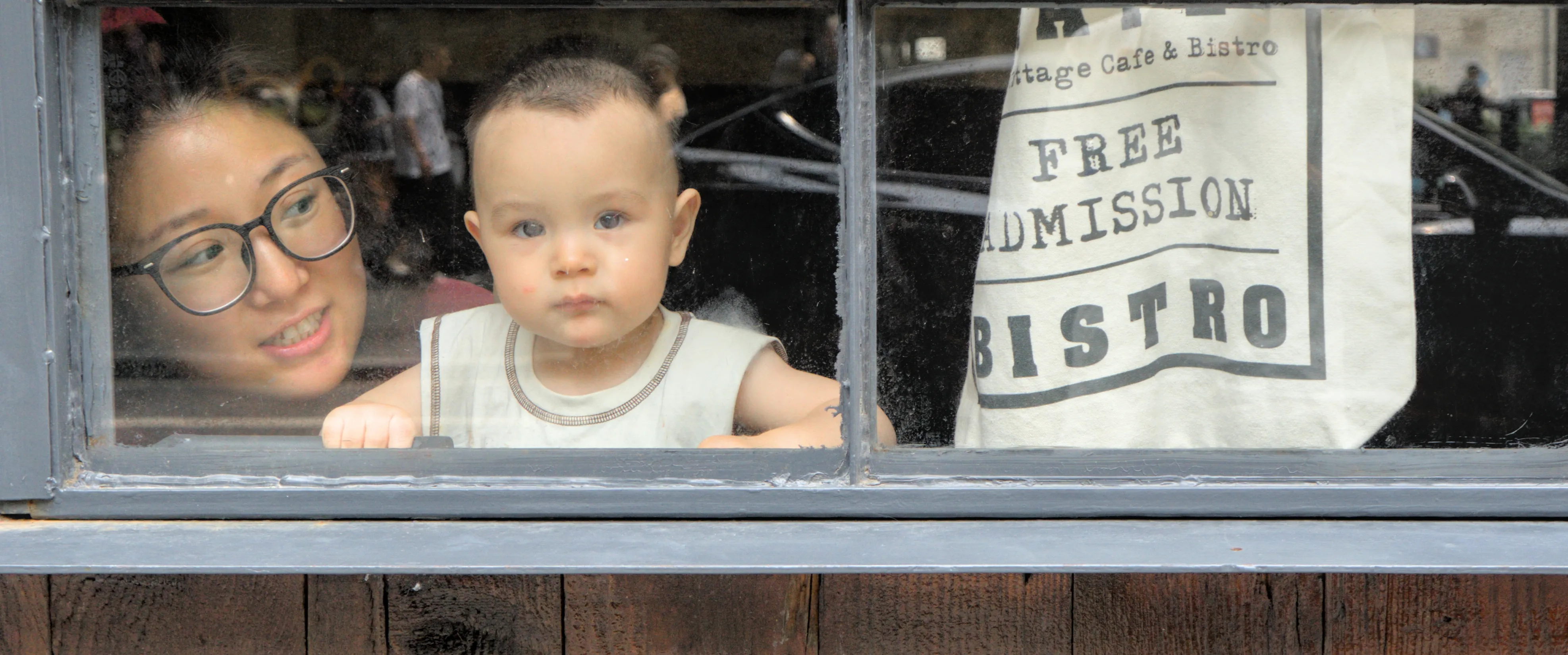 A boy and his mother looking out the window of a café