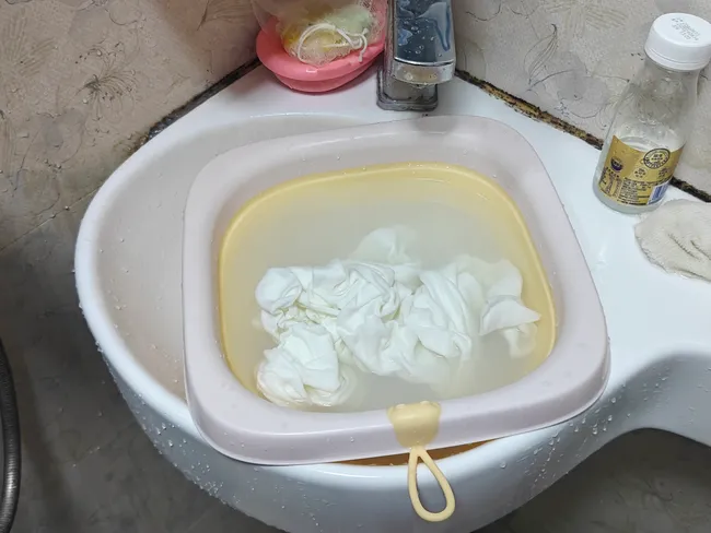 A small tub of water in a sink, filled with cloth diapers