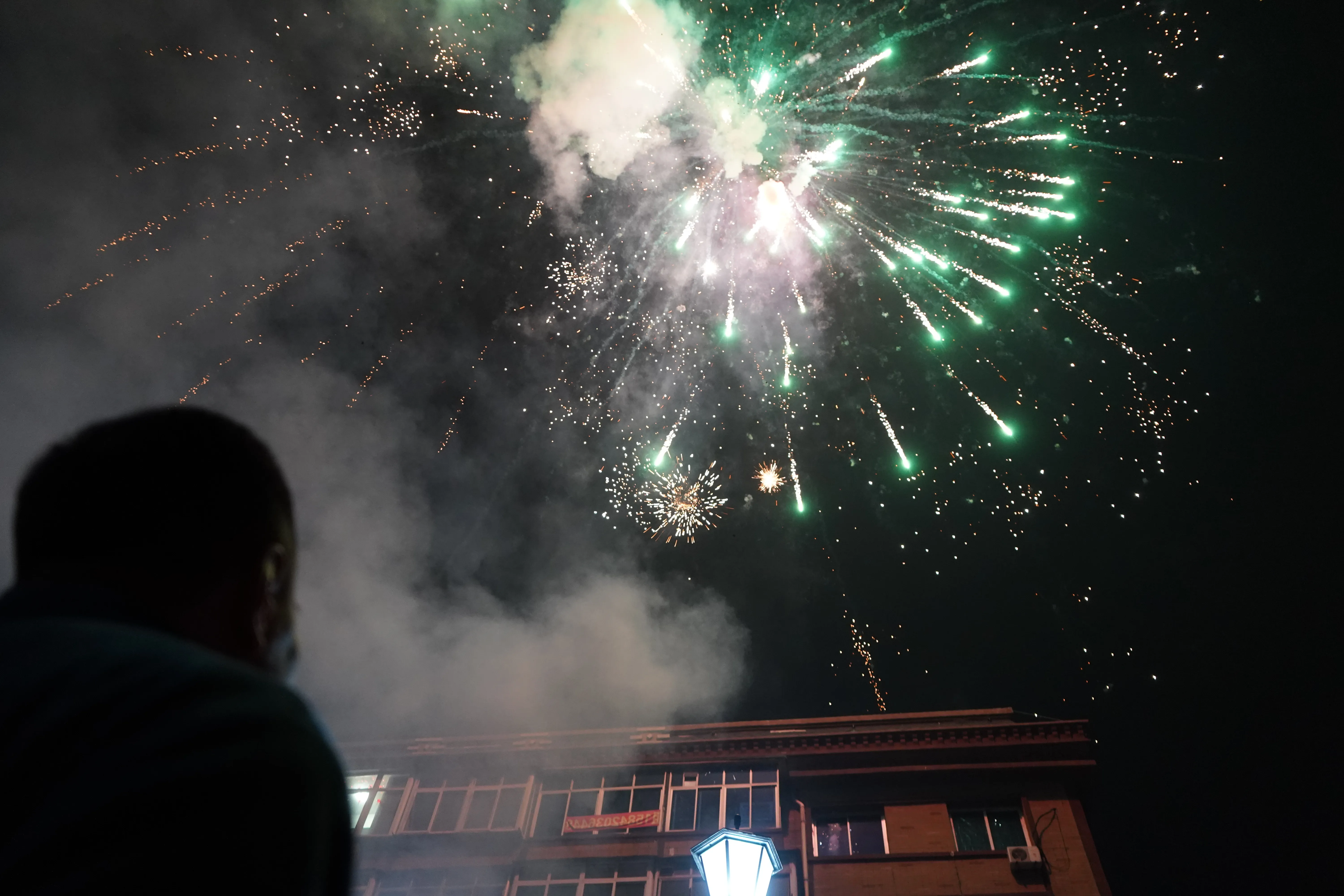 Fireworks illuminating the façades of neighboring apartment buildings during Chinese New Year's Eve.