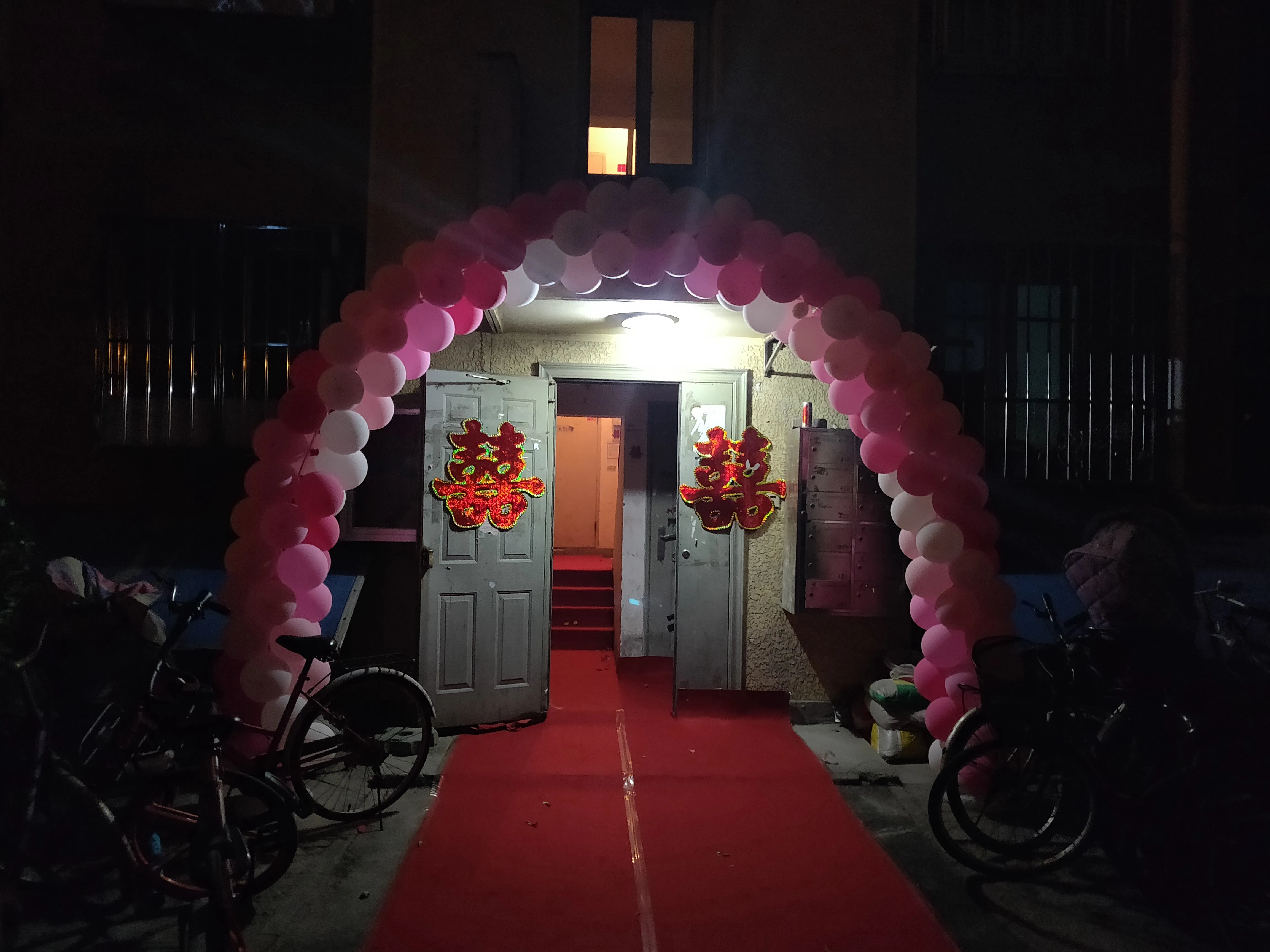 Wedding decorations outside an apartment entrance at night.
