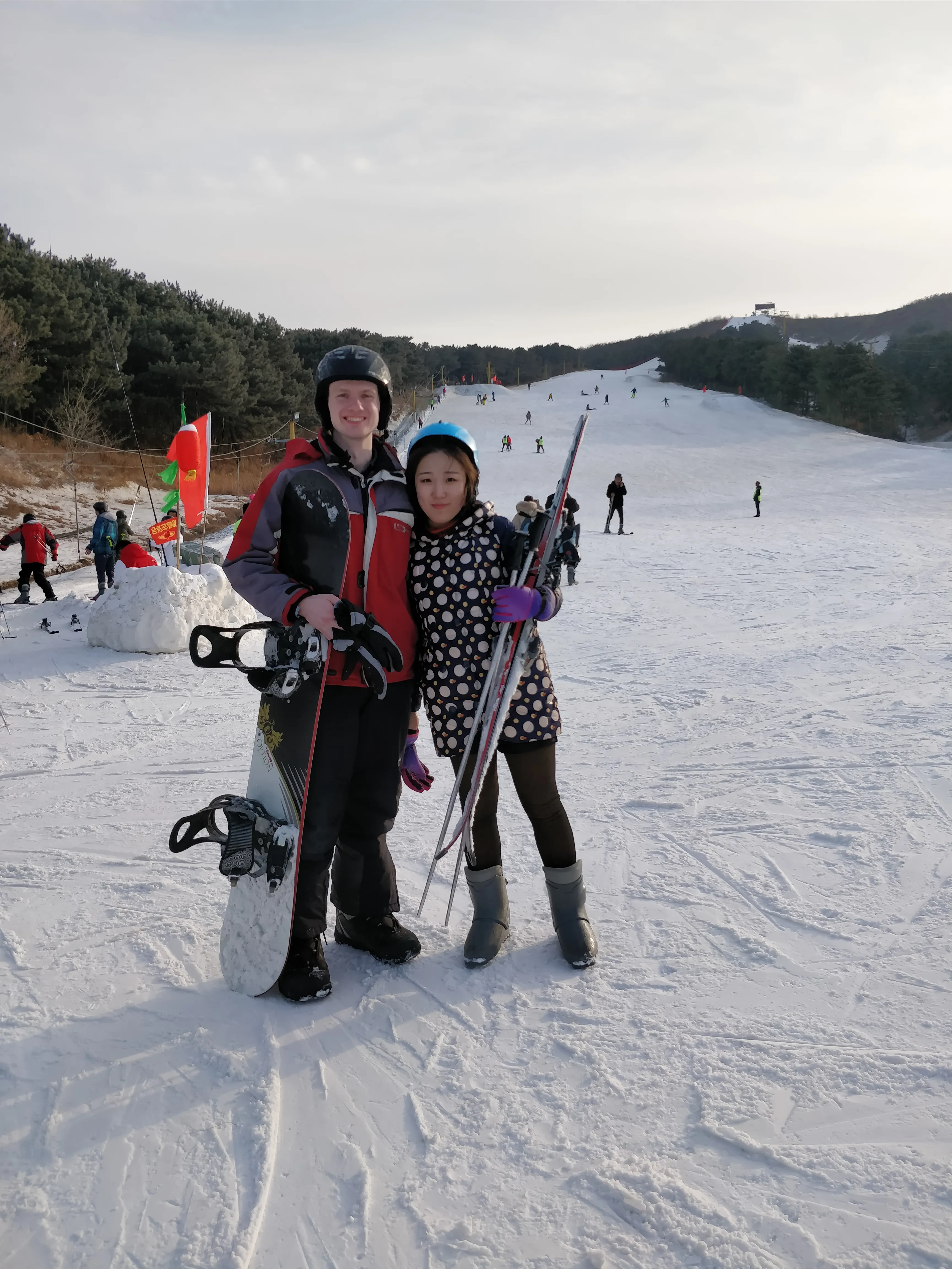 Two people with ski gear on a snowy slope.