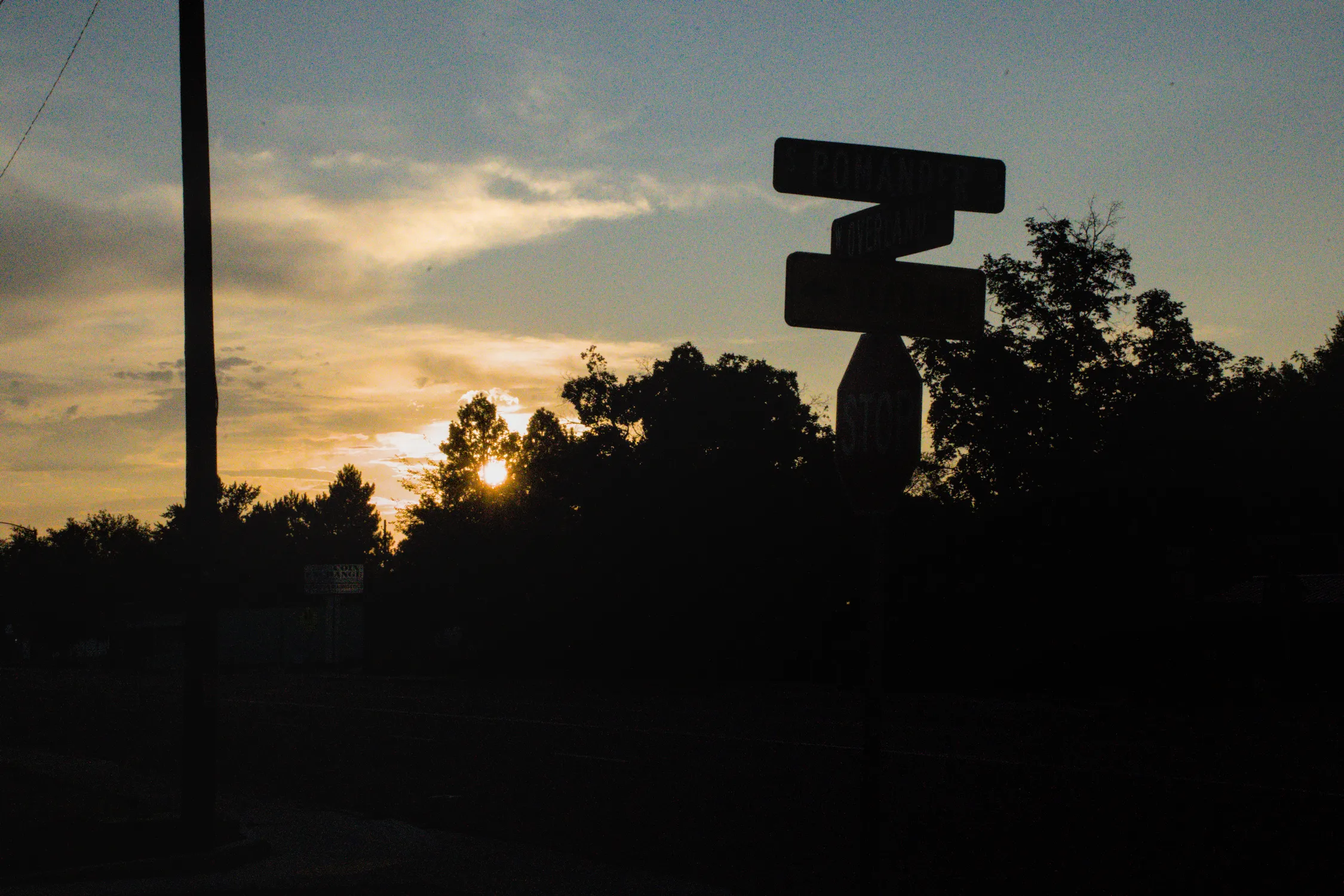 A street sign backlit by a sunset