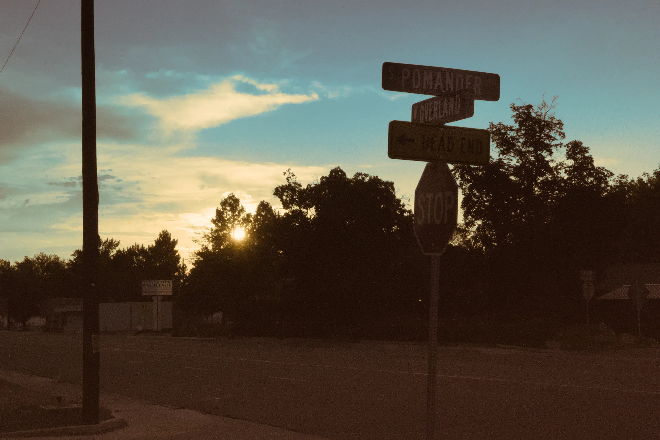 A street sign with a sunset with a split tone effect