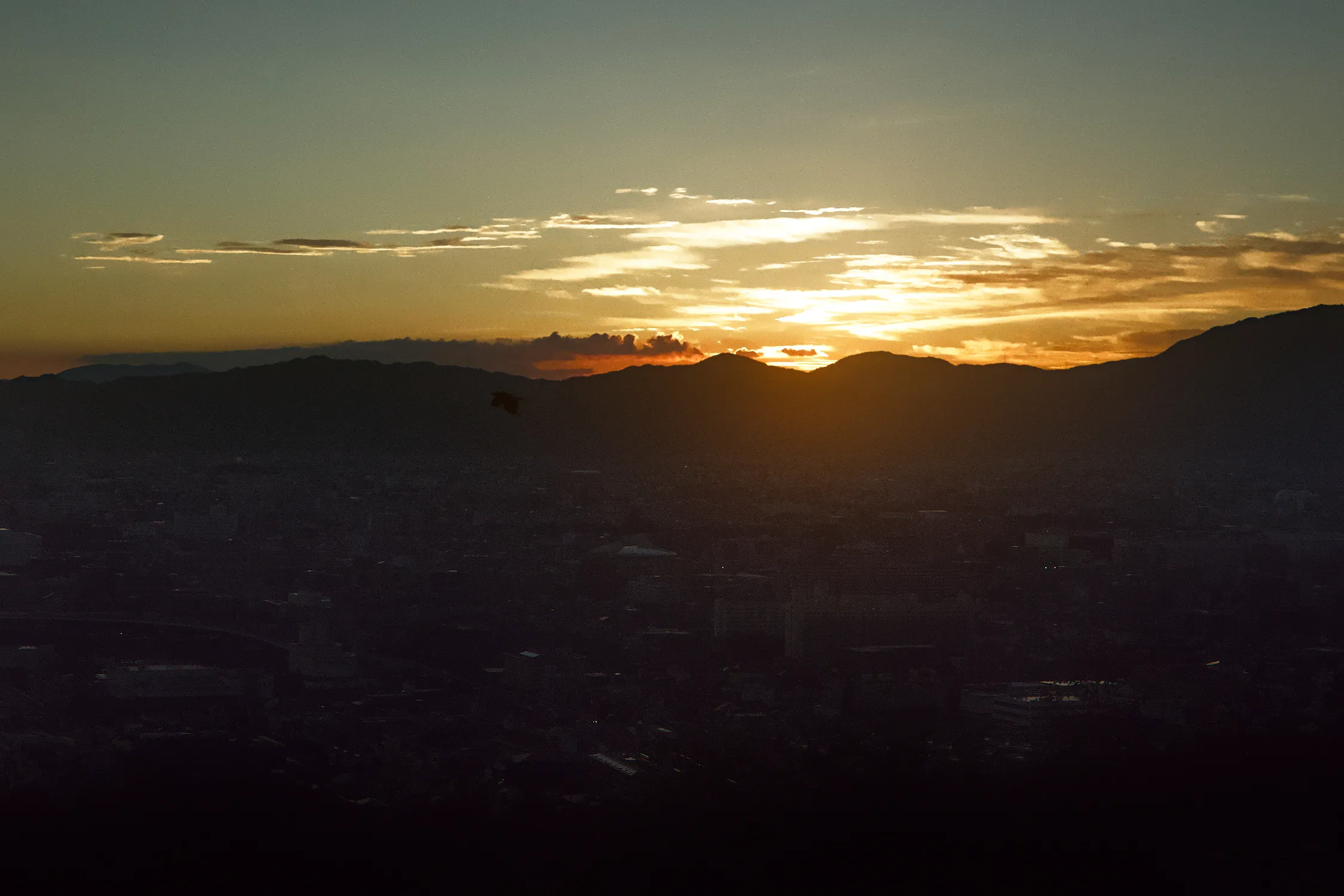 Sunset over mountains with the city in shadow