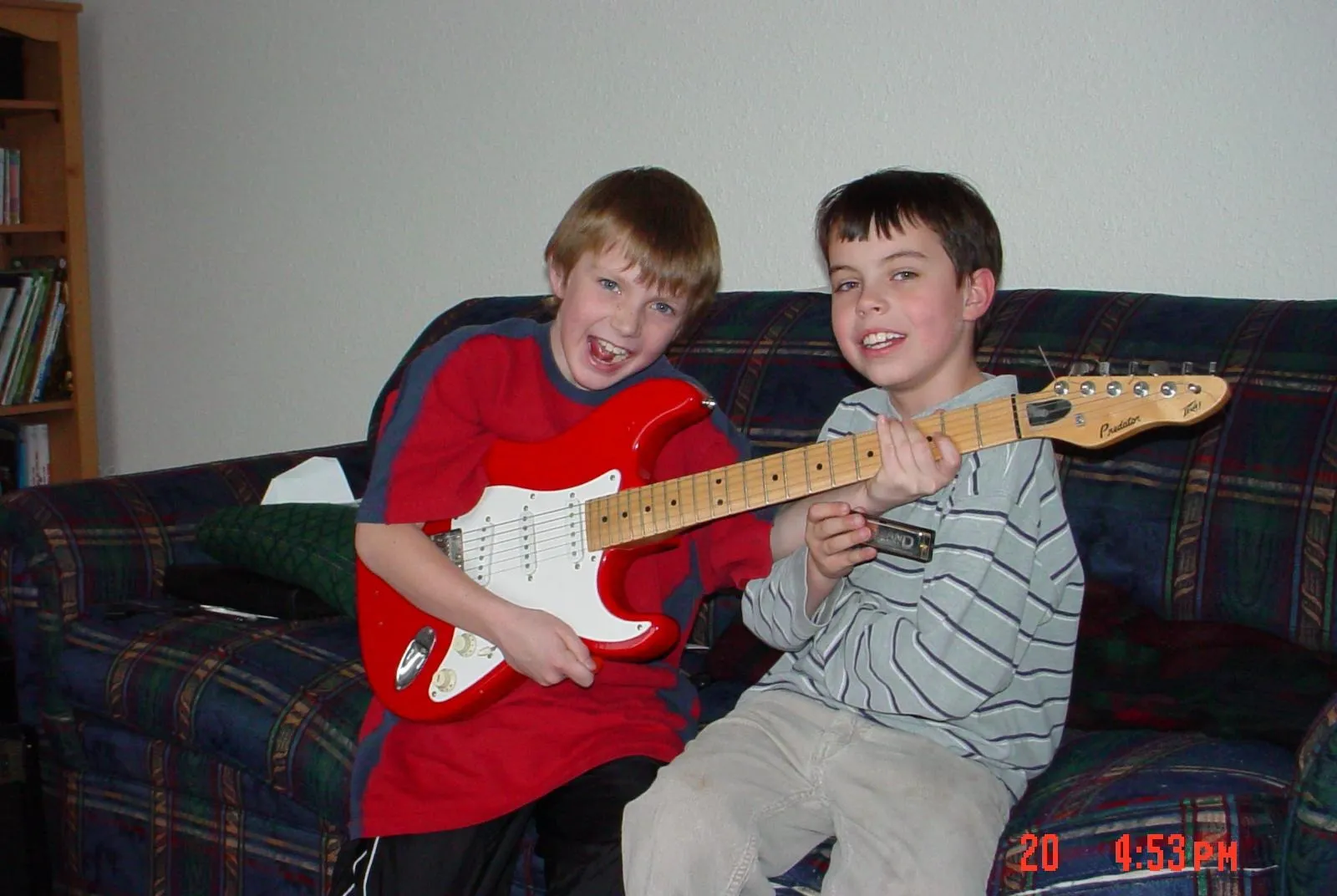 A photo of a boy with a red guitar and his friend